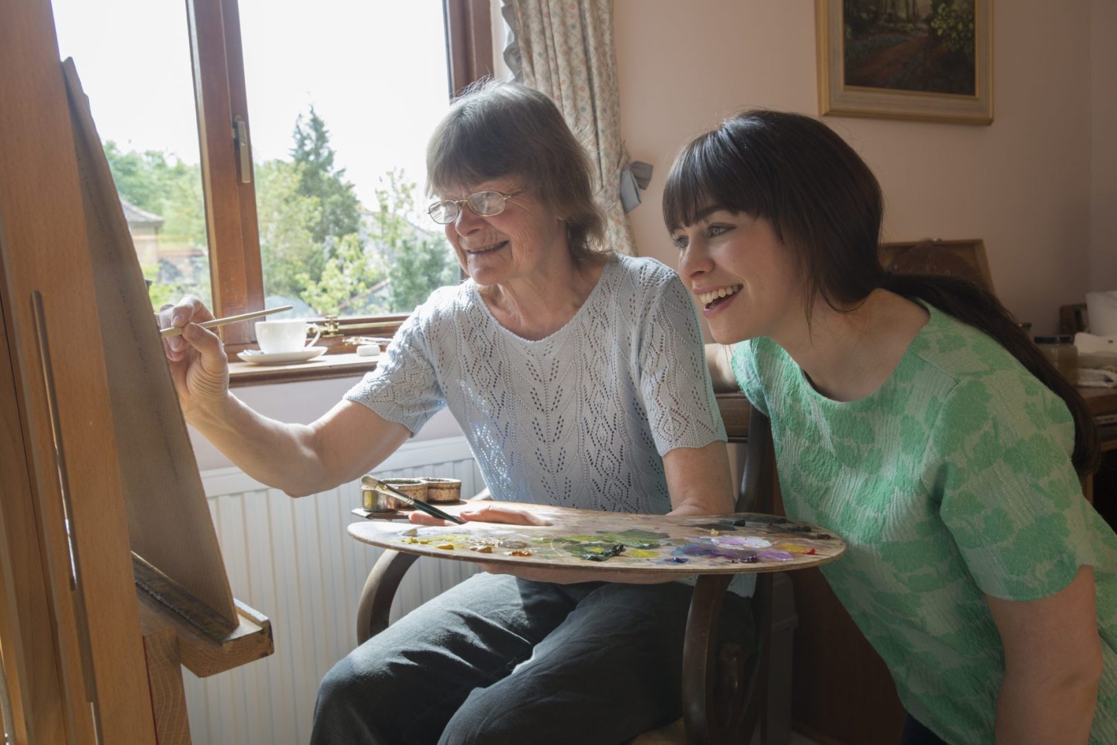 Women painting with the help of in-care help